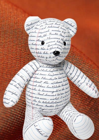 A bear sewn from fabric printed with a handwritten letter